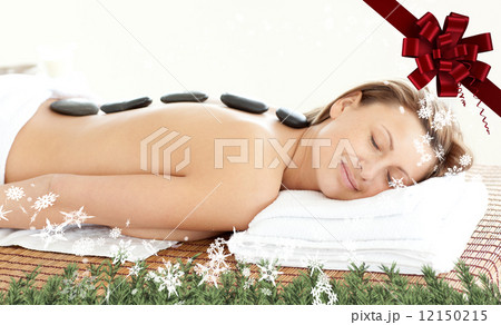 Composite image of radiant woman with hot stones on her back Composite image of radiant woman with hot stones on her back 12150215