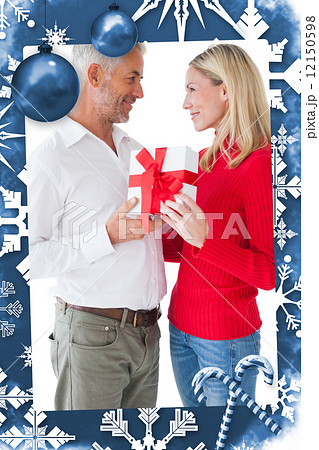 Composite image of smiling couple embracing and holding gift 12150598
