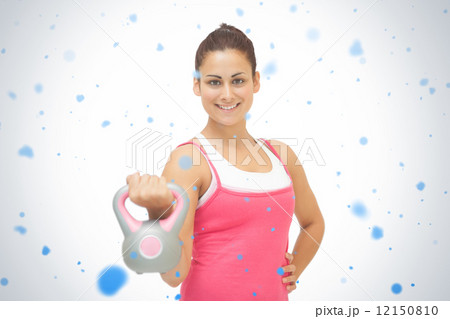 Cheerful sporty brunette holding grey and pink kettlebell Cheerful sporty brunette holding grey and pink kettlebell 12150810