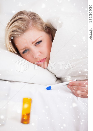 Sick young woman holding a thermometer 12150950