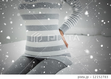 Mid section of a woman with back ache sitting in bed Mid section of a woman with back ache sitting in bed 12152783