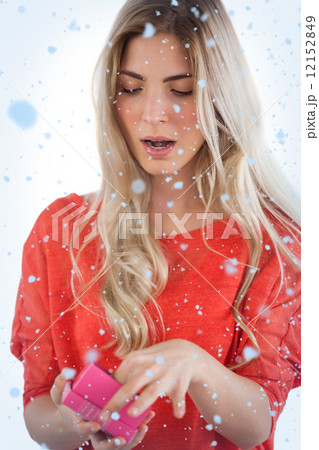 Composite image of surprised woman opening her gift Composite image of surprised woman opening her gift 12152849
