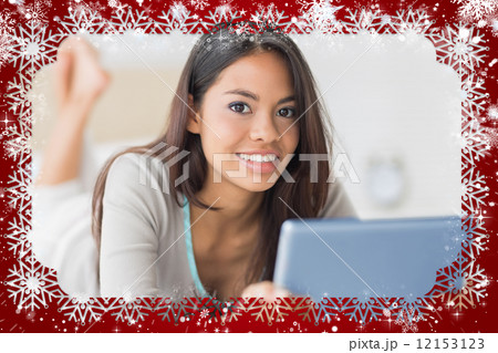 Pretty girl lying on bed using her tablet pc smiling at camera 12153123