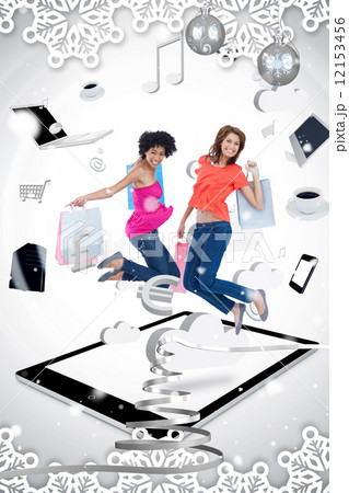 Two smiling women jumping on a tablet pc 12153456