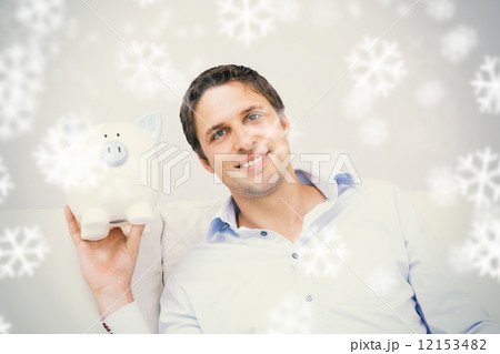 Handsome casual man with piggy bank in living room 12153482