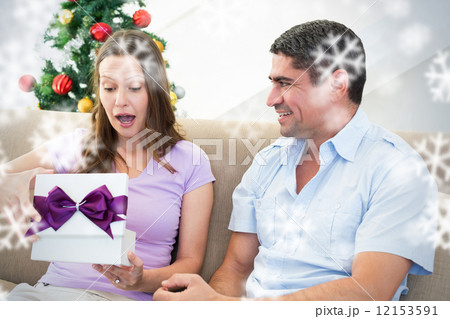 Composite image of surprised woman opening christmas present Composite image of surprised woman opening christmas present 12153591