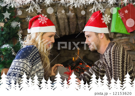 Man gifting woman in front of lit fireplace during christmas 12153620
