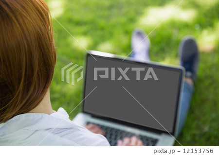 Pretty redhead using her laptop in the park Pretty redhead using her laptop in the park 12153756