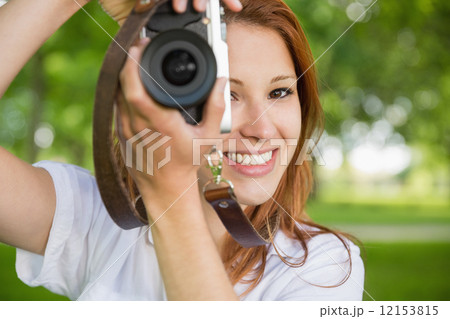 Pretty redhead taking a photo in the park Pretty redhead taking a photo in the park 12153815