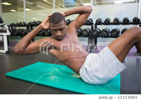 Shirtless man doing abdominal crunches in gym Shirtless man doing abdominal crunches in gym 12153905