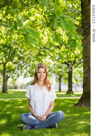 Pretty redhead smiling at camera in the park 12154003
