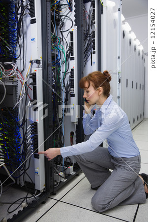 Serious technician talking on phone while analysing server 12154027