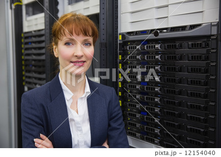 Pretty technician smiling at camera beside server tower 12154040