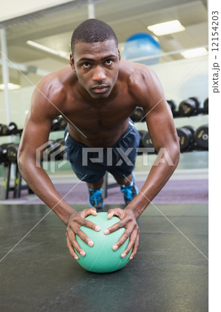 Determined man doing push ups with ball in gym Determined man doing push ups with ball in gym 12154203