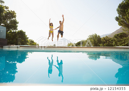 Cheerful couple jumping into swimming pool Cheerful couple jumping into swimming pool 12154355
