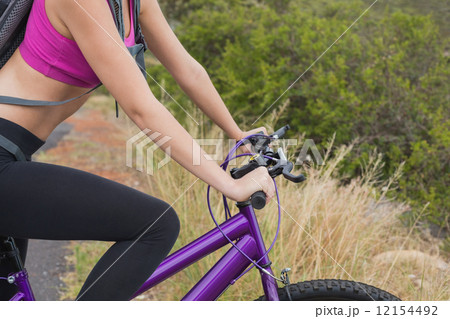 Side view of athletic woman mountain biking 12154492