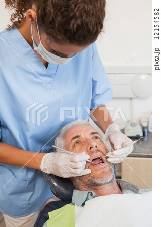 Dentist examining a patients teeth in the dentists chair 12154582