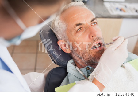 Dentist examining a patients teeth in the dentists chair Dentist examining a patients teeth in the dentists chair 12154940
