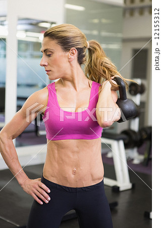 Fit woman lifting kettle bell in gym Fit woman lifting kettle bell in gym 12155312
