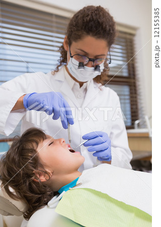 Pediatric dentist examining a little boys teeth in the dentists Pediatric dentist examining a little boys teeth in the dentists 12155385