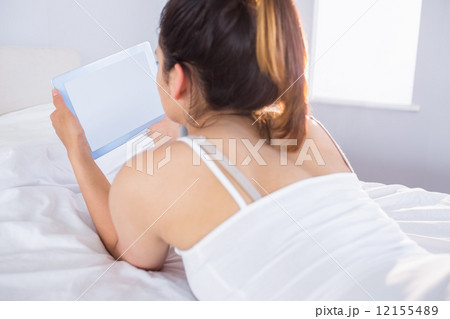 Relaxed woman using digital tablet in bed Relaxed woman using digital tablet in bed 12155489