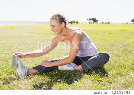 Fit mature woman warming up on the grass 12155593