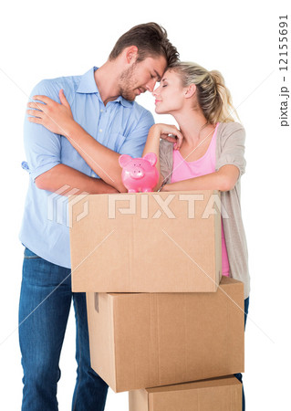 Attractive young couple leaning on boxes with piggy bank 12155691