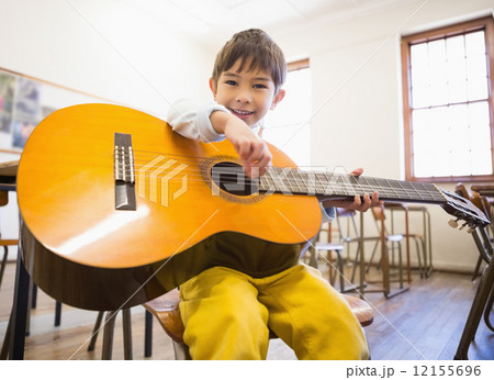 Cute pupil playing guitar in classroom 12155696
