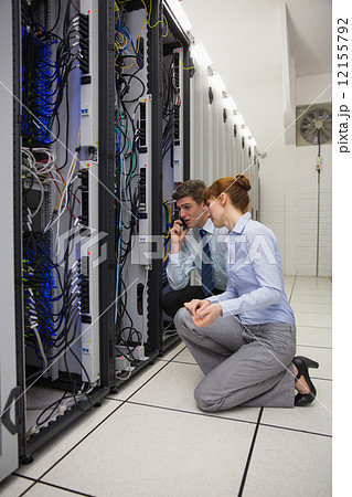Team of technicians kneeling and looking at servers Team of technicians kneeling and looking at servers 12155792