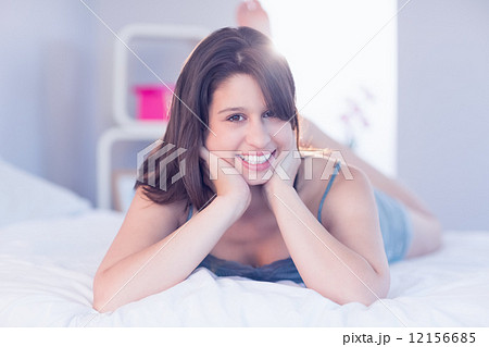Beautiful brunette lying on bed smiling at camera Beautiful brunette lying on bed smiling at camera 12156685