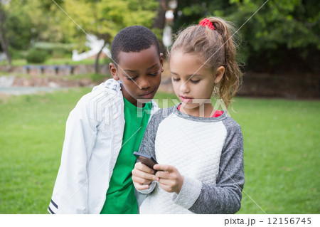 Cute little children looking at smartphone Cute little children looking at smartphone 12156745