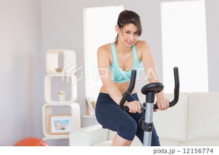 Fit brunette working out on exercise bike 12156774