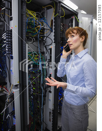 Technician talking on phone while analysing server 12157085