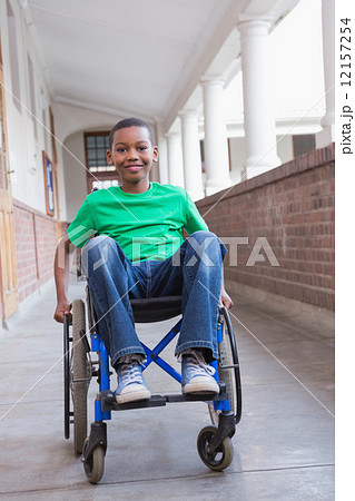Cute disabled pupil smiling at camera in hall 12157254