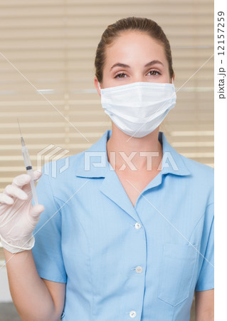 Dental assistant holding injection looking at camera Dental assistant holding injection looking at camera 12157259
