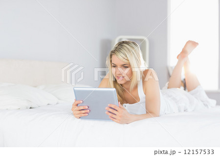 Relaxed beautiful woman using digital tablet in bed 12157533