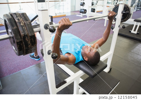 Determined young man lifting barbell in gym Determined young man lifting barbell in gym 12158045