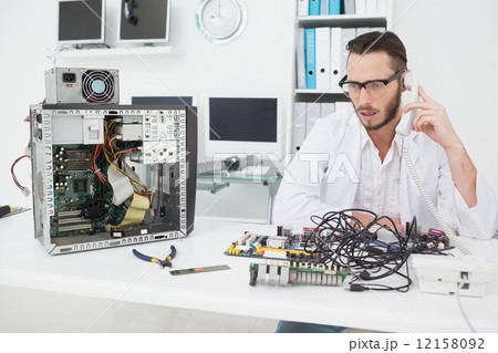 Computer engineer looking at broken device and making a phone ca 12158092