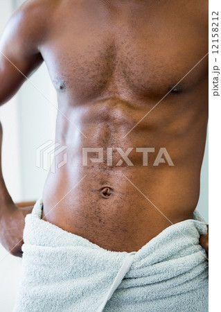 Mid section of a shirtless muscular man in gym Mid section of a shirtless muscular man in gym 12158212