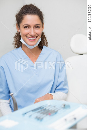 Dentist smiling at camera beside chair 12158230