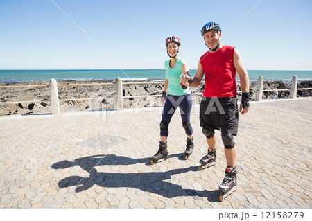 Fit mature couple rollerblading on the pier 12158279