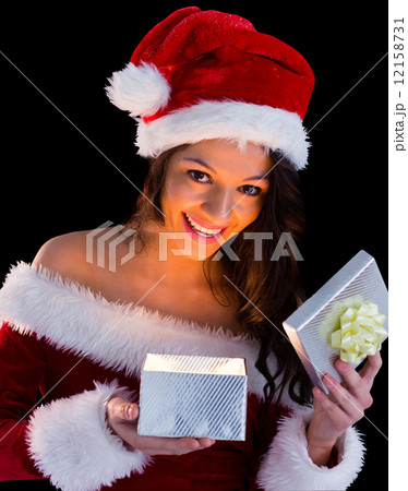 Pretty brunette in santa outfit opening gift 12158731