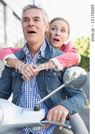 Happy senior couple riding a moped Happy senior couple riding a moped 12158889