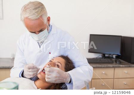 Dentist examining a patients teeth in the dentists chair 12159046
