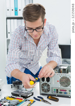 Young technician working on broken computer Young technician working on broken computer 12159048