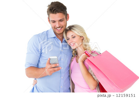 Attractive young couple holding shopping bags looking at smartph 12159151