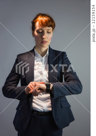Businesswoman in suit checking the time Businesswoman in suit checking the time 12159154