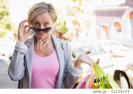 Happy mature woman smiling at camera with her shopping purchases 12159155