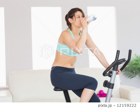 Fit brunette working out on exercise bike 12159222
