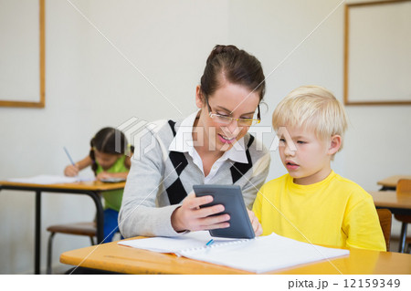 Pretty teacher helping pupil in classroom Pretty teacher helping pupil in classroom 12159349